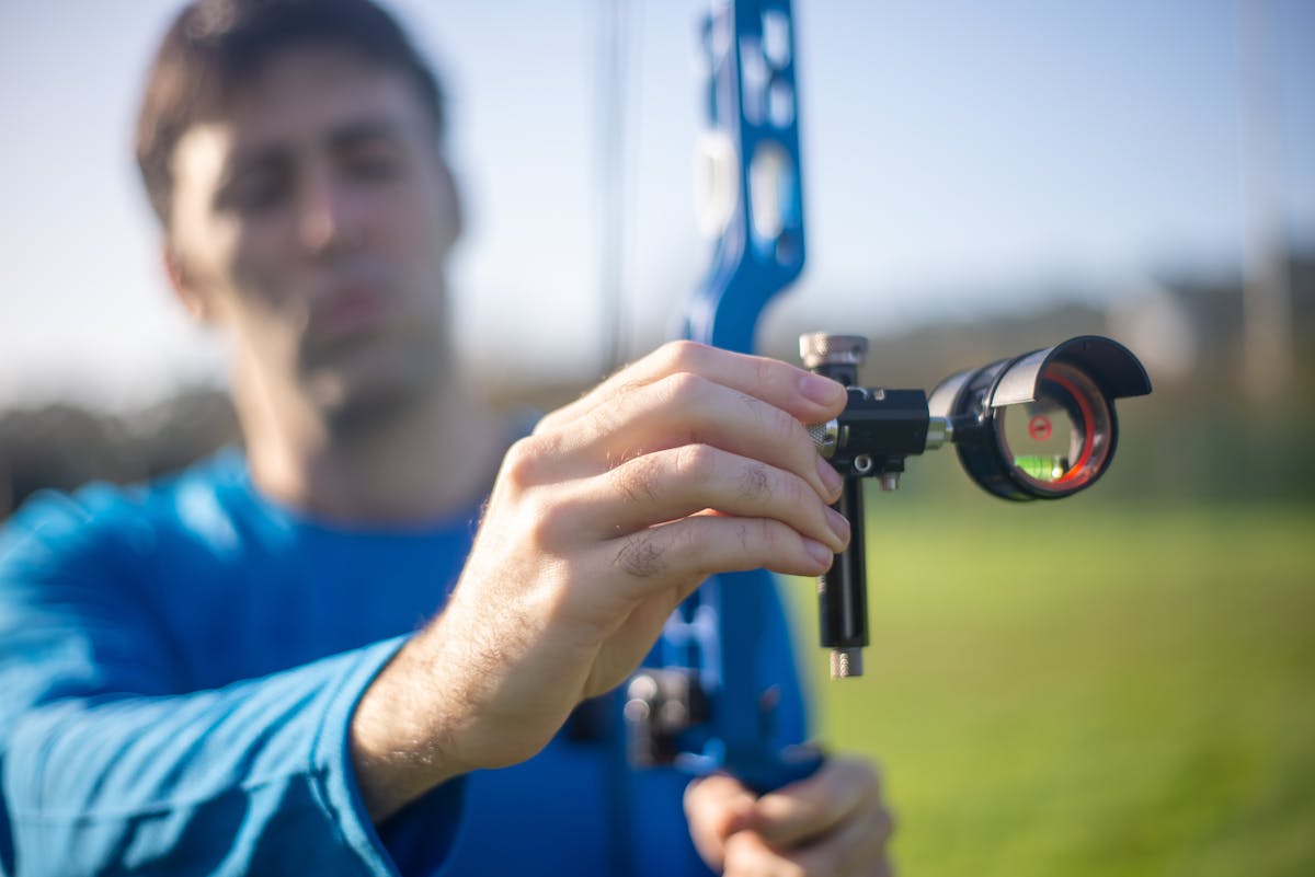Archer adjusting windage knob on bow sight for left-right arrow placement correction
