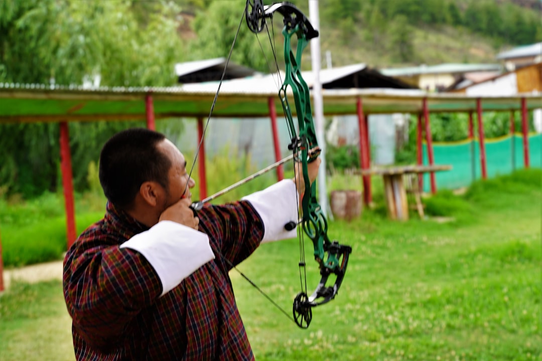 Archer at full draw with compound bow stabilizer setup