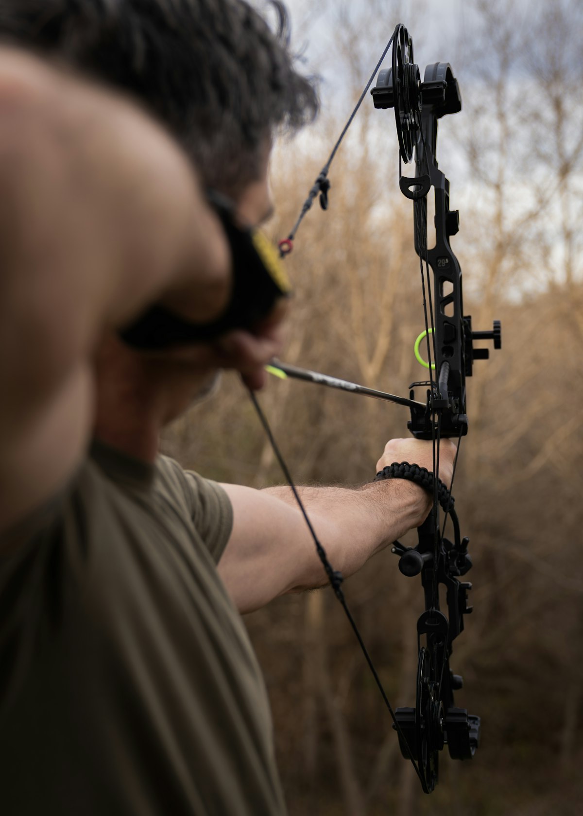 Bowhunter aiming compound bow outdoors preparing for elk archery season