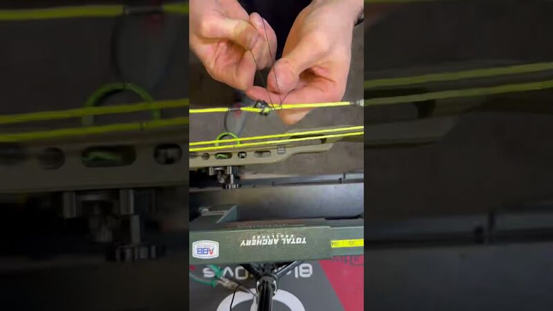 Close-up of compound bow peep sight alignment on bowstring