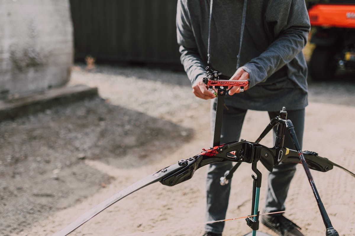 Person setting up a modern compound bow outdoors for tuning adjustments