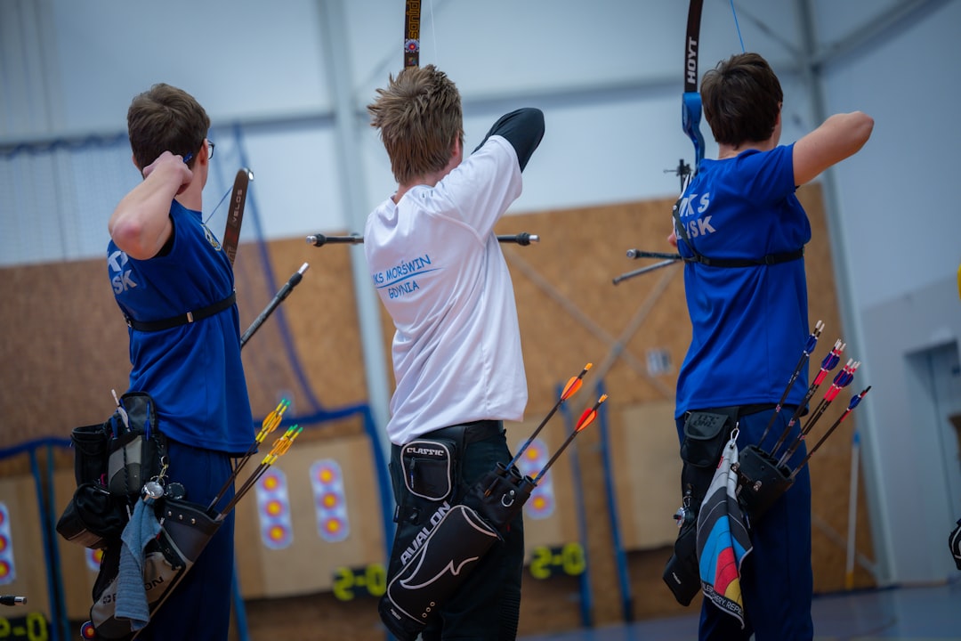 Three archers practicing proper shooting stance at indoor archery range