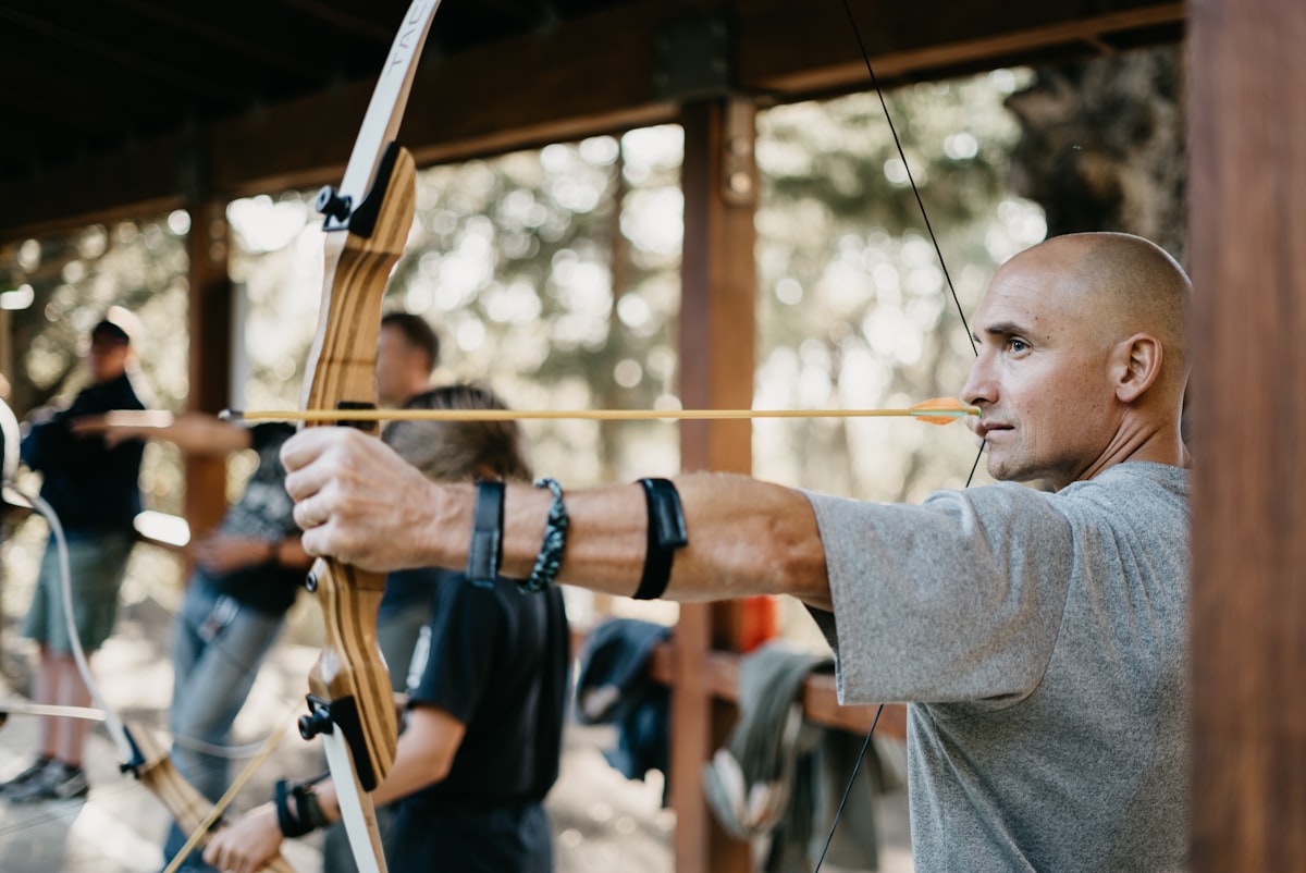 Male archer drawing a traditional bow engaging back and shoulder muscles
