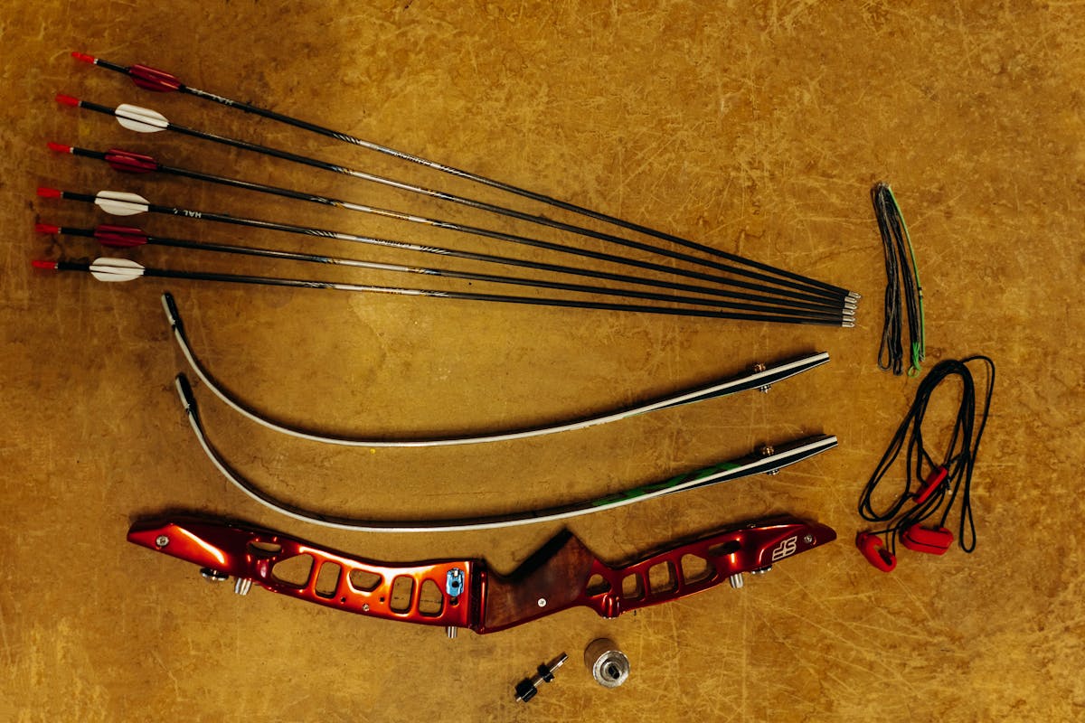 Disassembled recurve bow and carbon arrow components showing shaft nock and point for arrow selection