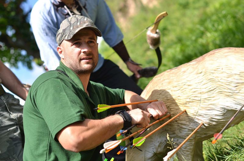 Bowhunter pulling arrows from a 3D archery target on a wooded course
