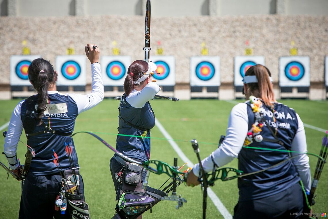 Three women compound archers on the shooting line each using their dominant eye