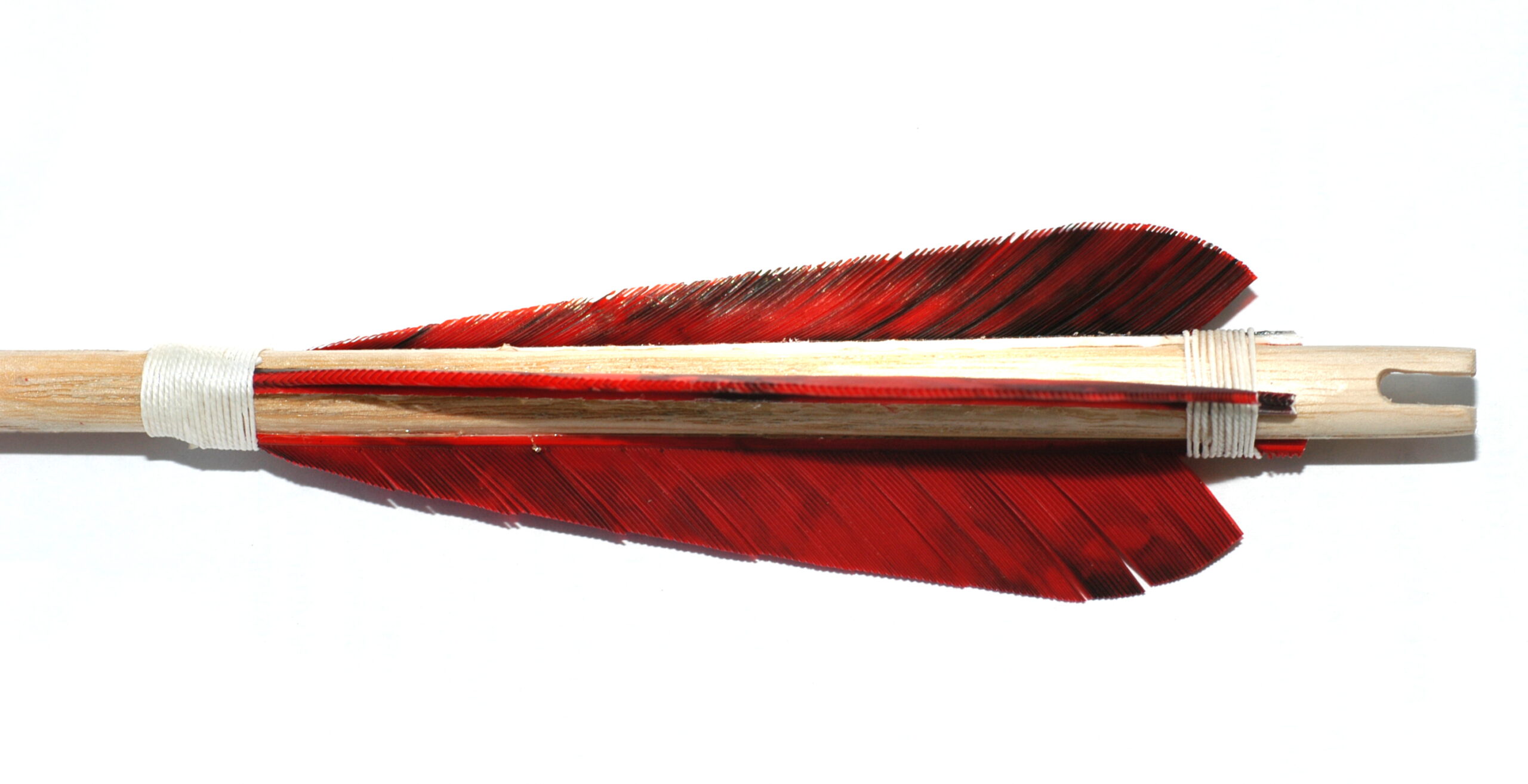 close-up of arrow fletching feathers being applied to arrow shaft with winding string