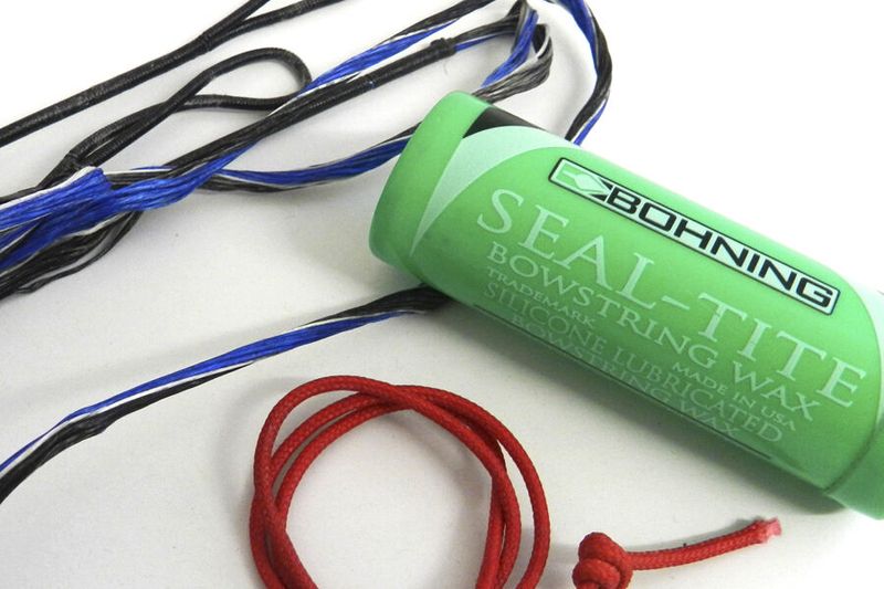 Bohning bowstring wax tube next to worn recurve cable strands