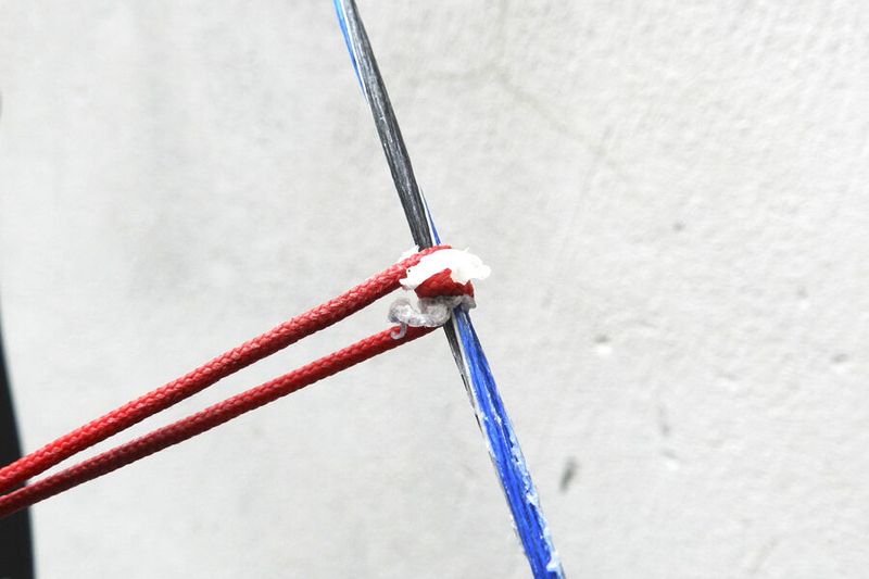 Buffing wax into a compound bow string to extend bow string life