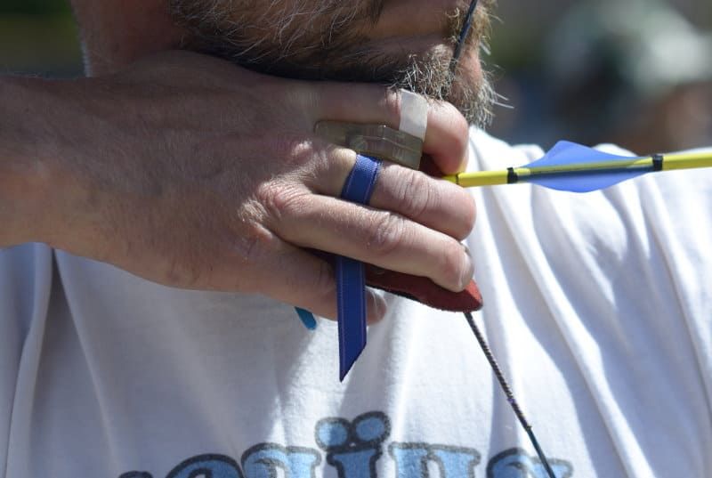 Recurve archer at full draw — string wear accumulates with every shot