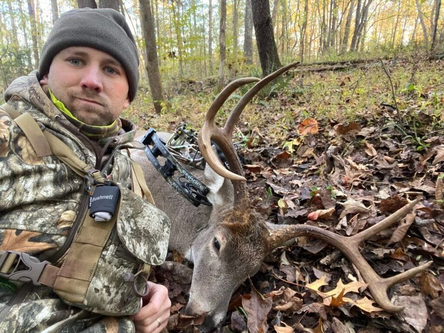 Bowhunter posing with harvested whitetail buck taken with broadhead-tipped arrow