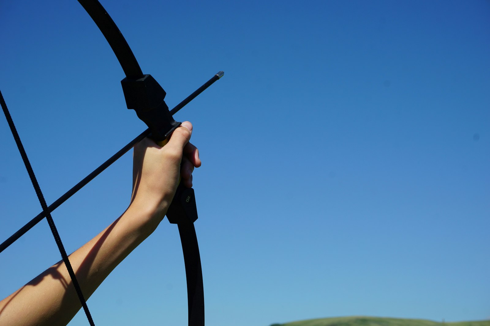 Compound bow held at full draw against blue sky for outdoor archery championship