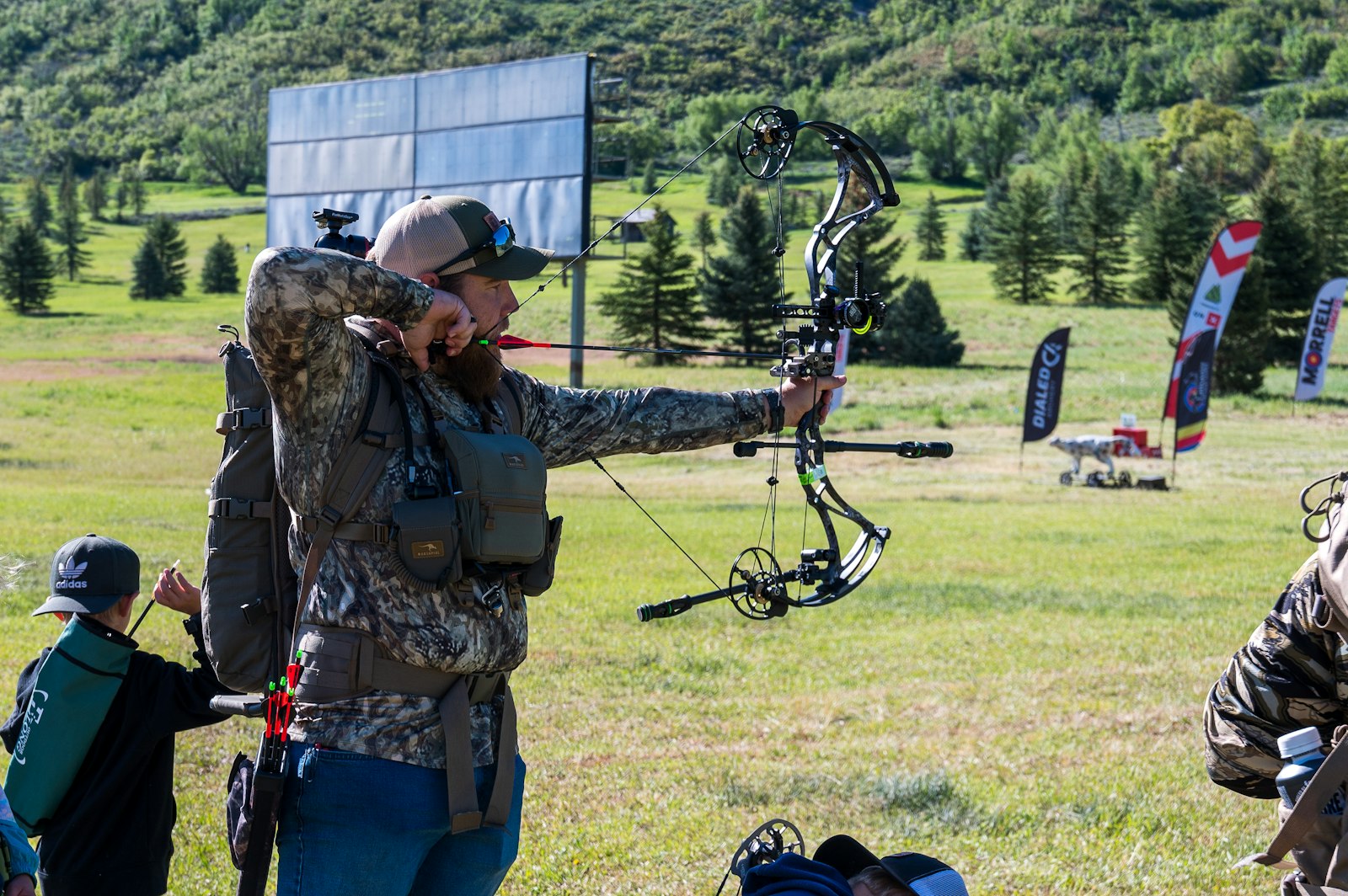 Compound bowhunter holding compound bow at full draw at outdoor field event