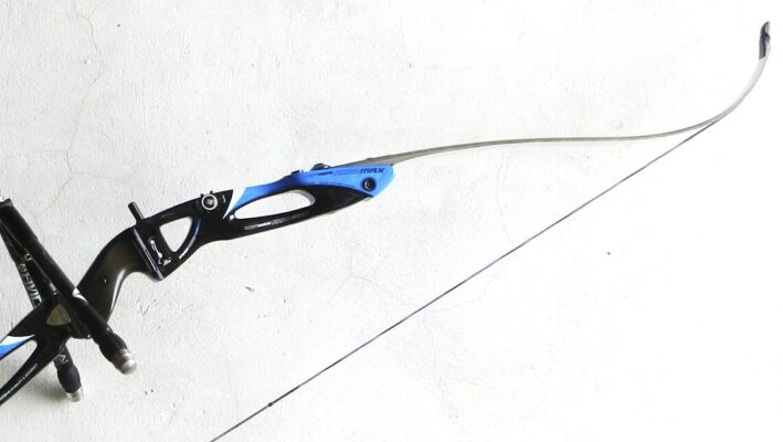 Archer with recurve bow and stabilizer leaned against wall — bowstring care equipment