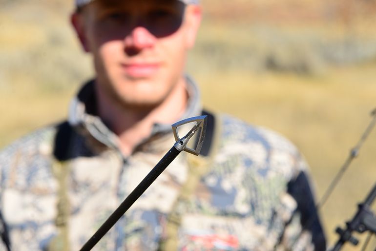 Bowhunter holding arrow with fixed blade broadhead in close-up shot
