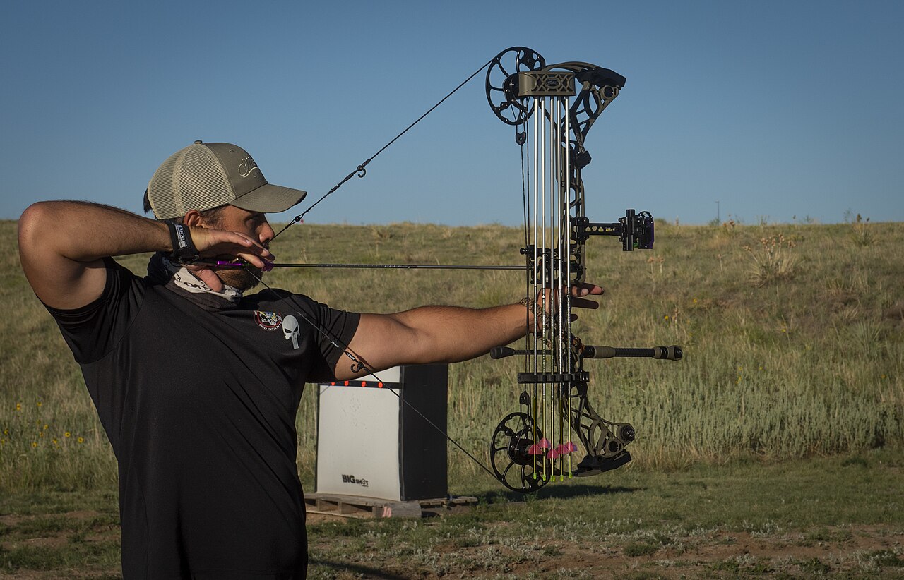 Archer sighting in a hybrid slider bow sight at an outdoor target range