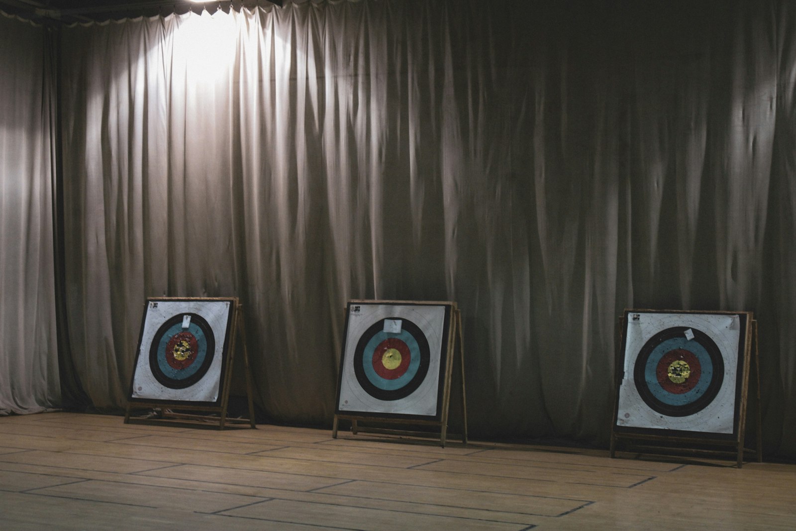 Indoor archery range with three target faces under spotlight for indoor world series