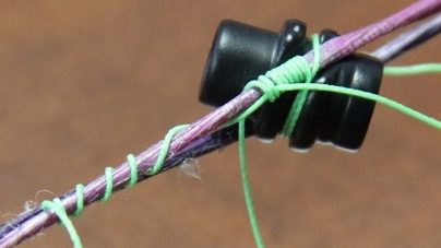 Peep sight tied into bow string with serving thread above and below