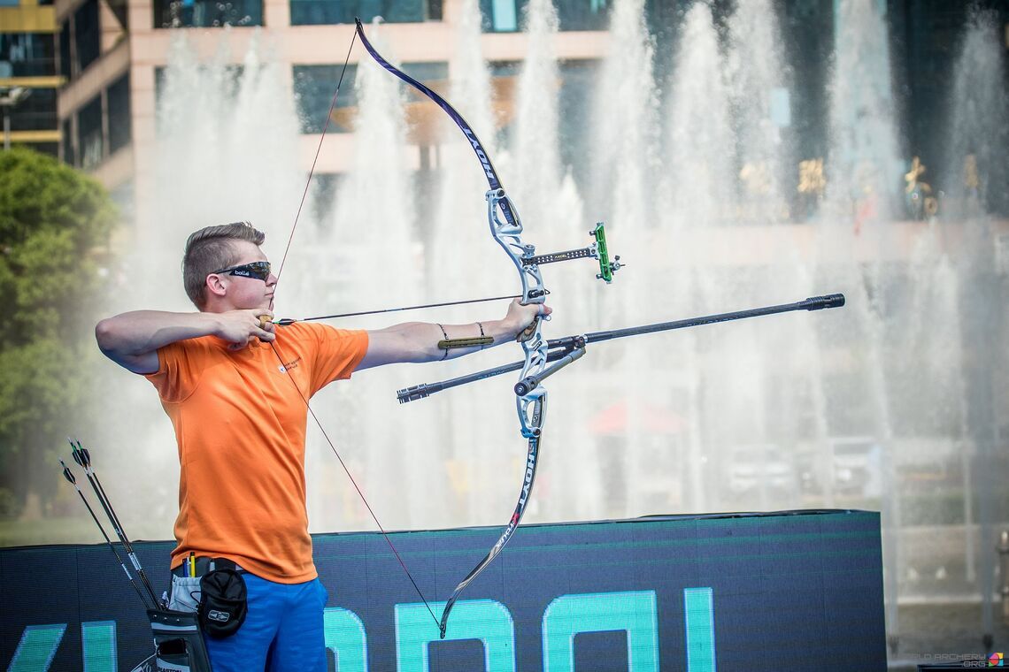 Recurve archer wearing sunglasses to manage eye dominance while aiming at the target