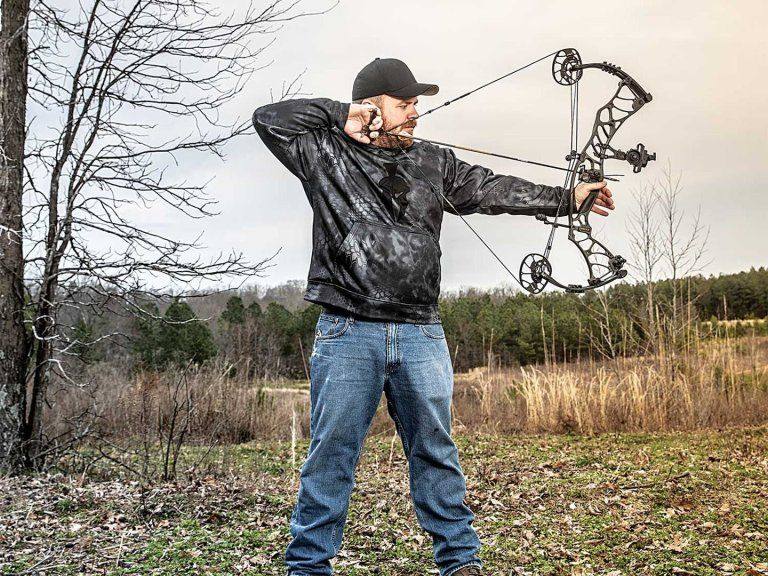Bowhunter at full draw using proper bow grip technique outdoors