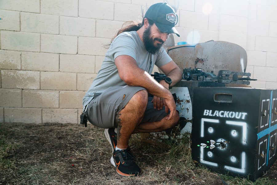Archer checking tight arrow groups in a foam target after sighting in a compound bow