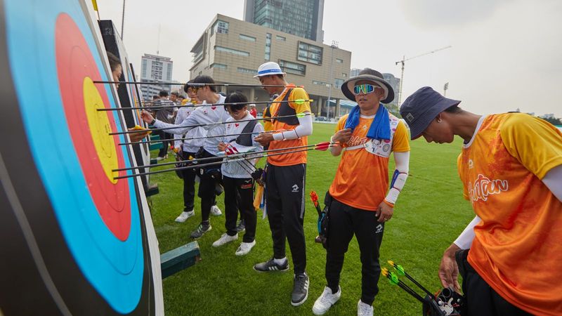 Recurve archers at outdoor competition where well-waxed bow strings matter