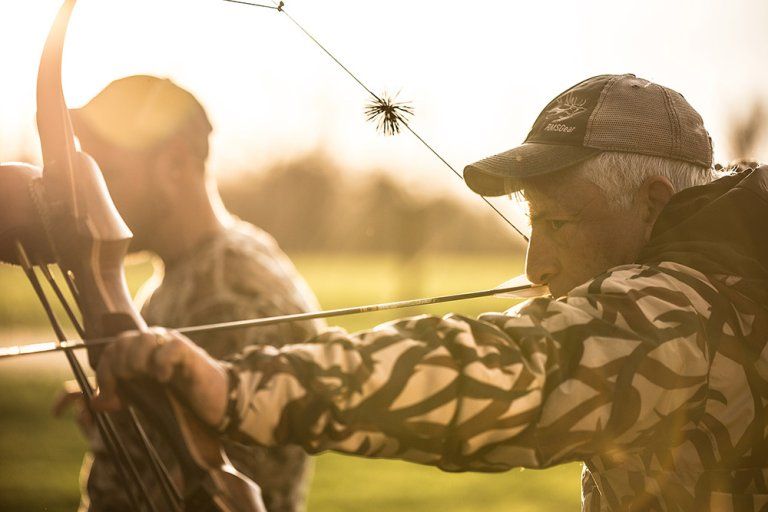 Archery bow grip and form on a traditional recurve bow at sunset
