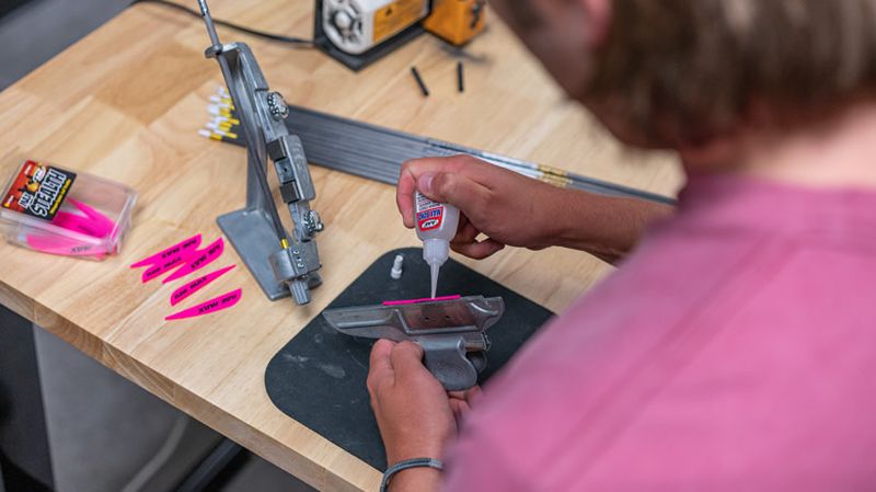 Arrow components and fletching jig laid out on workbench