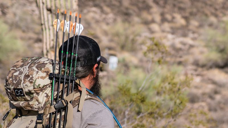 bowhunter carrying detached bow quiver mounted on hunting backpack