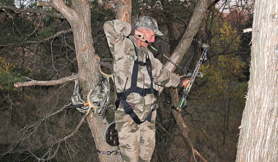 Bowhunter at full draw from a treestand after calling in a buck