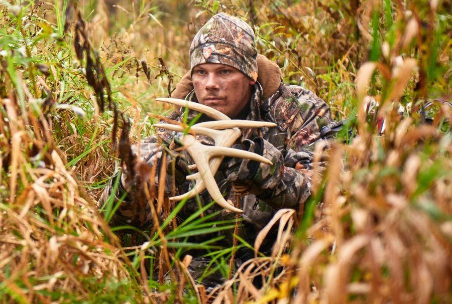 Bowhunter rattling antlers and using deer grunt call from ground level