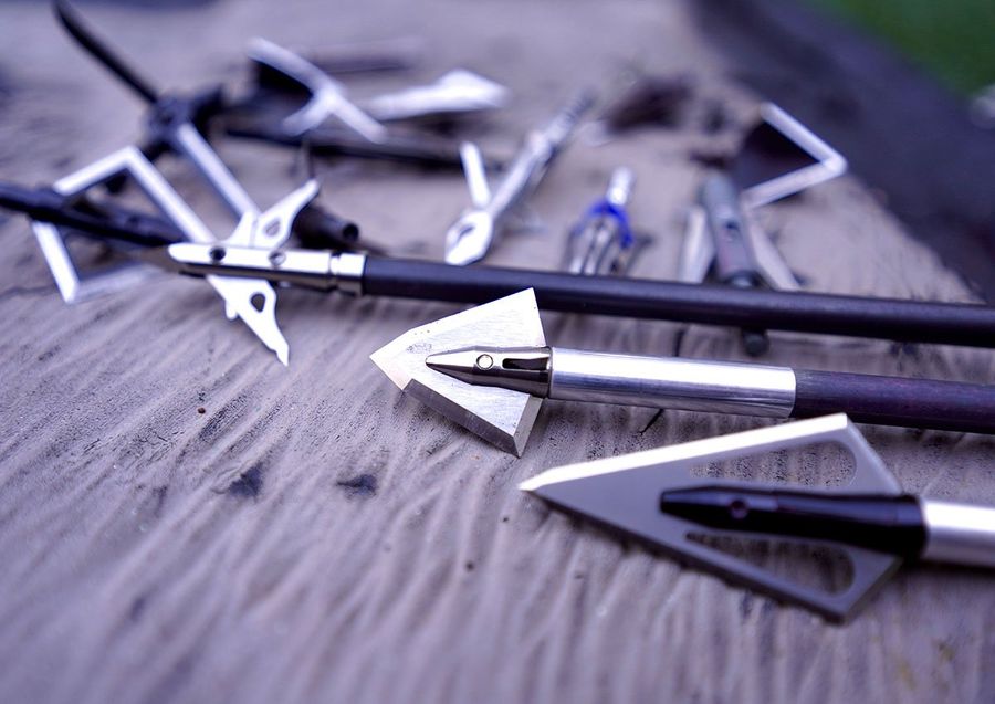 Selection of fixed blade and mechanical broadheads laid out on a workbench