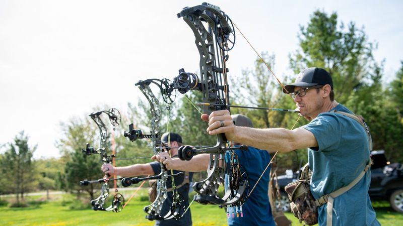 Compound bow archers at full draw on outdoor shooting line