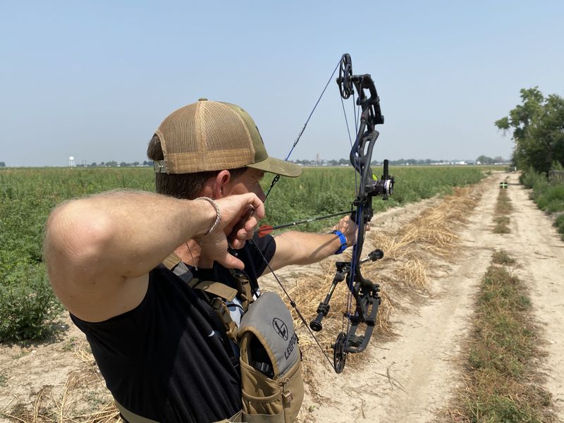 Archer shooting a compound bow down a field at effective range