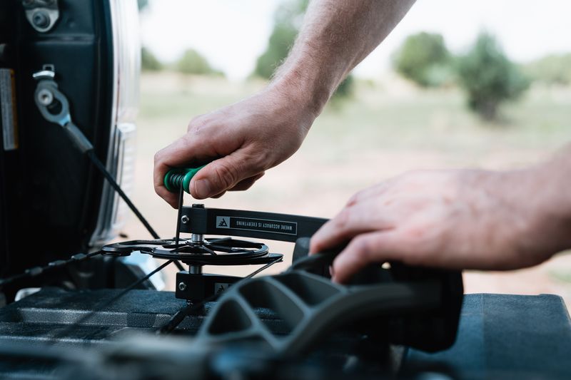Hands adjusting windage screws on a compound bow sight with hex wrench
