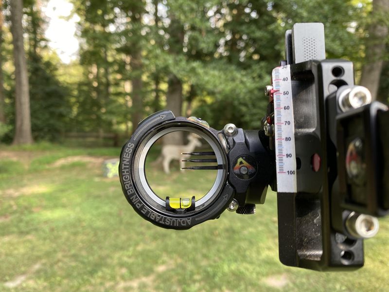 Compound bow sight with yardage pins aimed at a downrange target