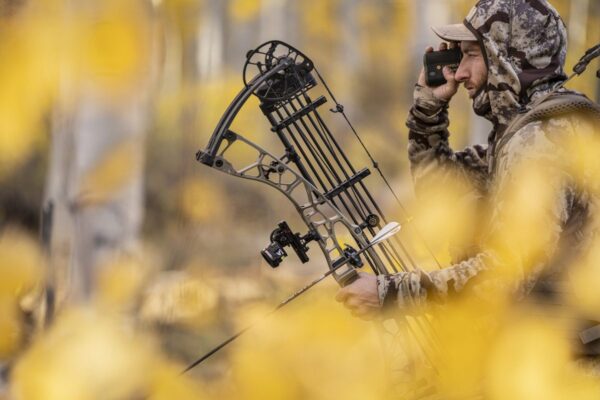 Bowhunter with compound bow in fall aspen woods comparing crossbow vs compound bow setups
