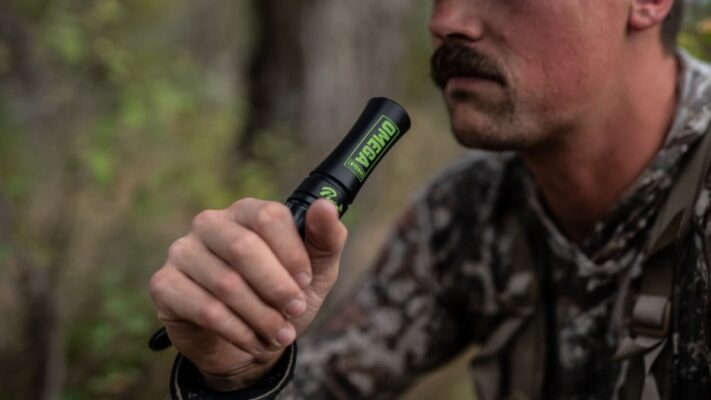 Bowhunter holding a deer grunt call tube in fall woods