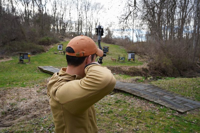 Archer demonstrating proper draw length adjustment on a compound bow at target range