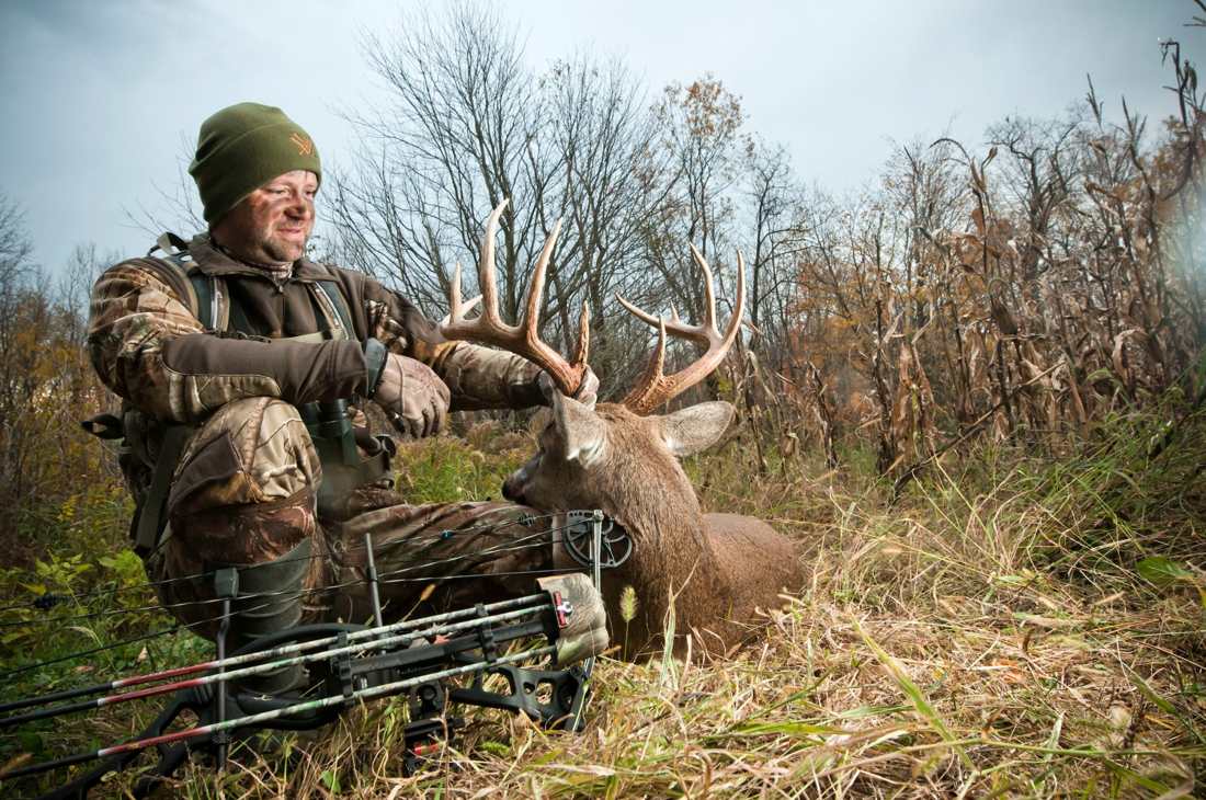 Bowhunter with a whitetail buck taken using proper draw weight for deer hunting