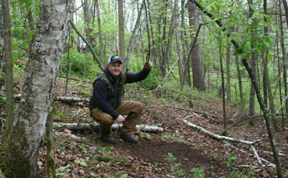 Bowhunter walking forest path scouting for mock scrape locations during whitetail bowhunting season