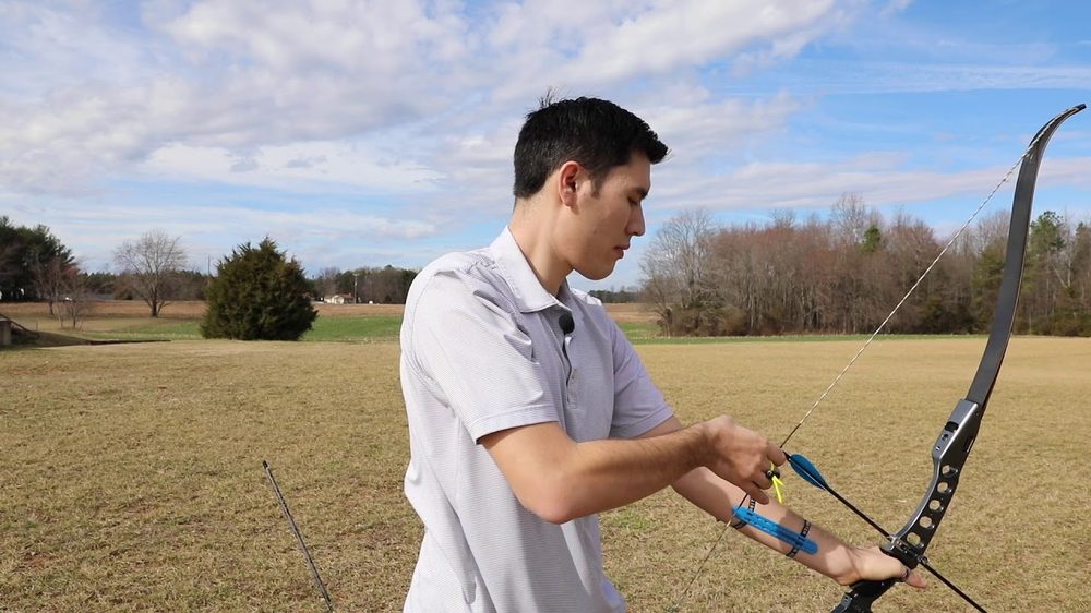 Archer nocking an arrow on a recurve bow for instinctive shooting