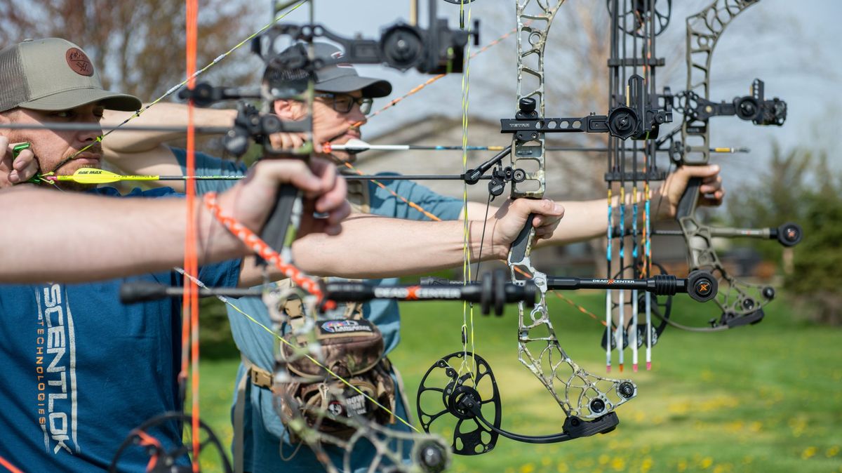 Proper bow grip in action — two archers at full draw on compound bows