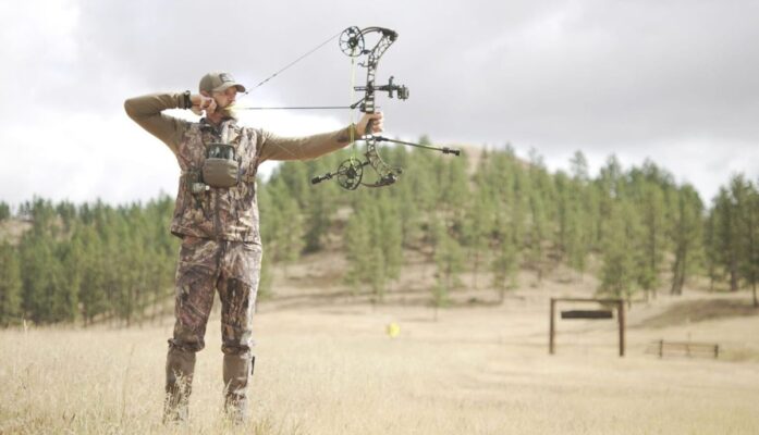 Bowhunter at full draw aiming a quiet compound bow in a field