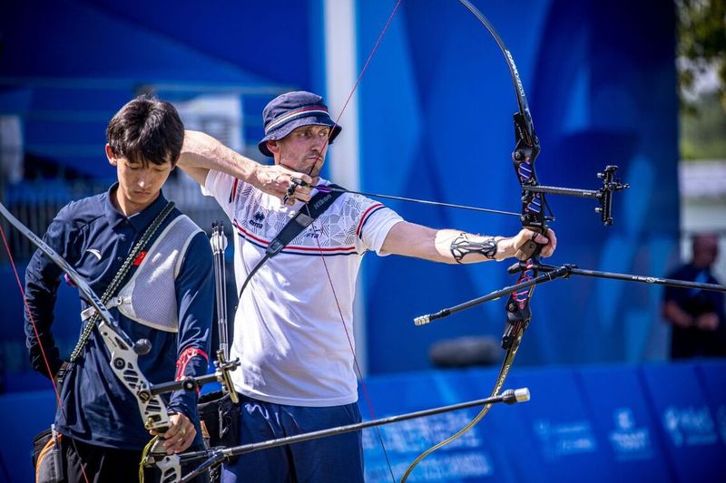 Recurve archer at full draw showing draw weight comparison to compound bow
