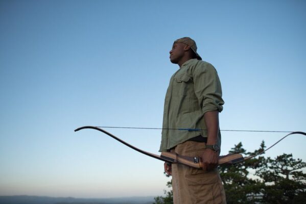 Archer holding a takedown recurve bow at sunset