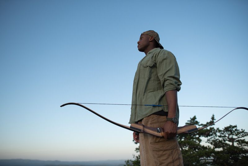 Archer holding a takedown recurve bow at sunset