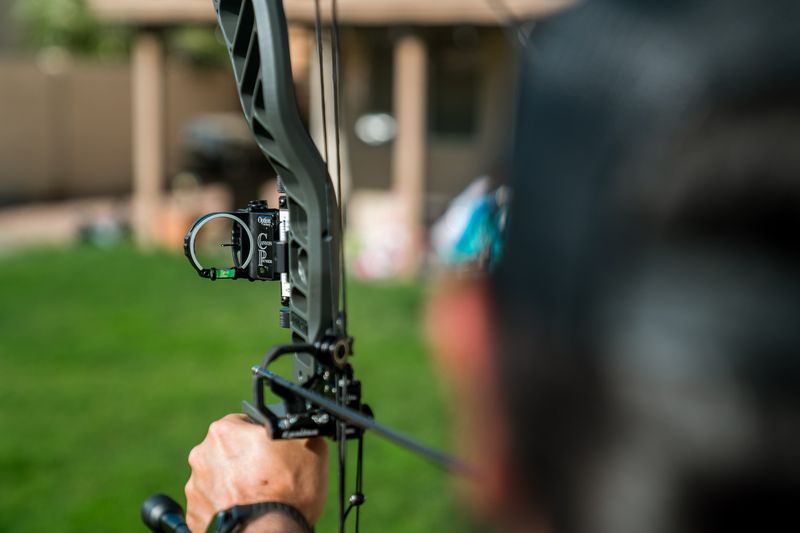 Single pin slider bow sight mounted on a hunting compound bow at full draw