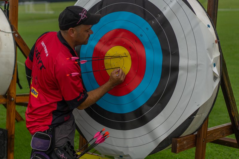 Target archer scoring arrows on a competition target face
