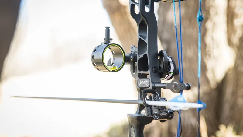 Compound bow sight close up aiming through pin and peep at target panic